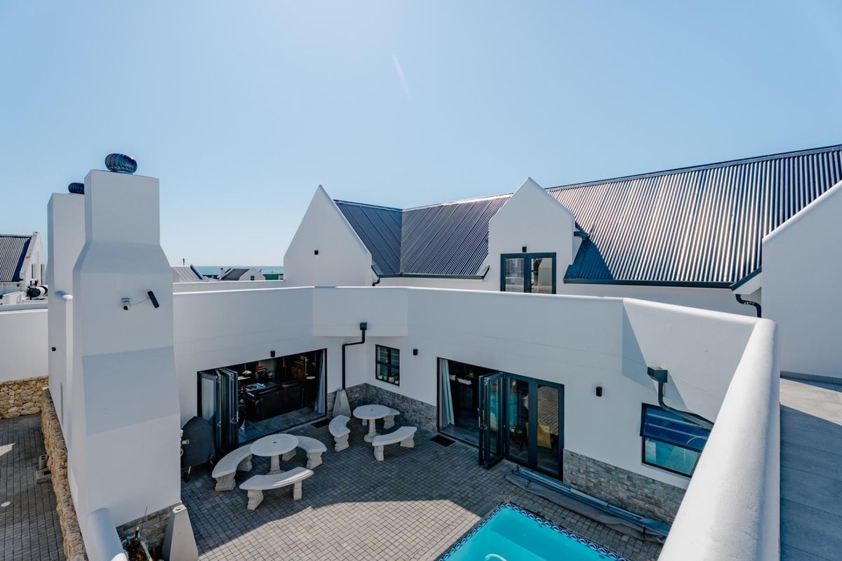 A well-maintained rear courtyard featuring a swimming pool, paved patio area, and modern architectural design with bi-fold doors connecting to the interior.