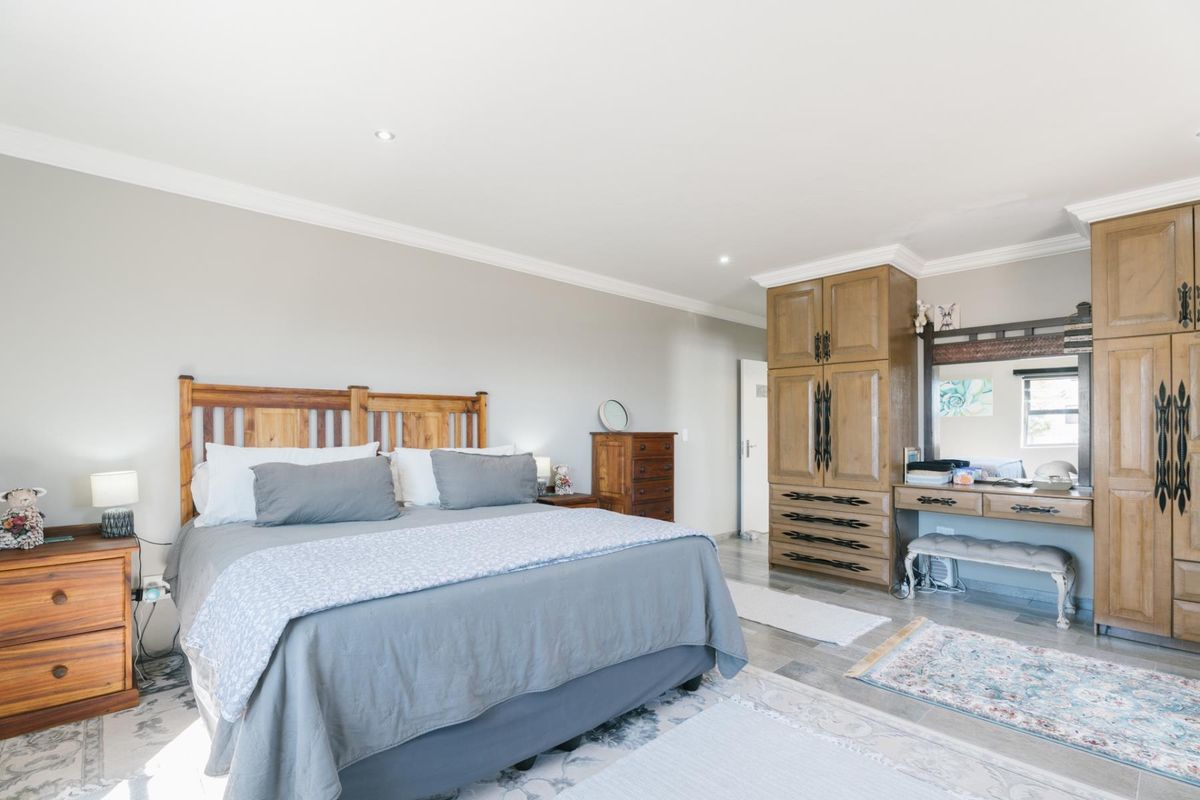Spacious bedroom featuring neutral walls, tiled flooring, recessed downlighting, and extensive built-in wooden cabinetry for ample storage.
