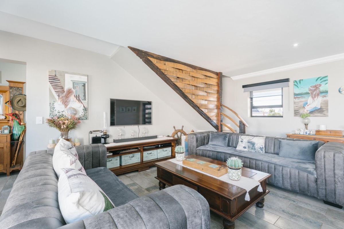 A comfortable living room featuring tiled flooring, recessed lighting, and a unique timber staircase design.