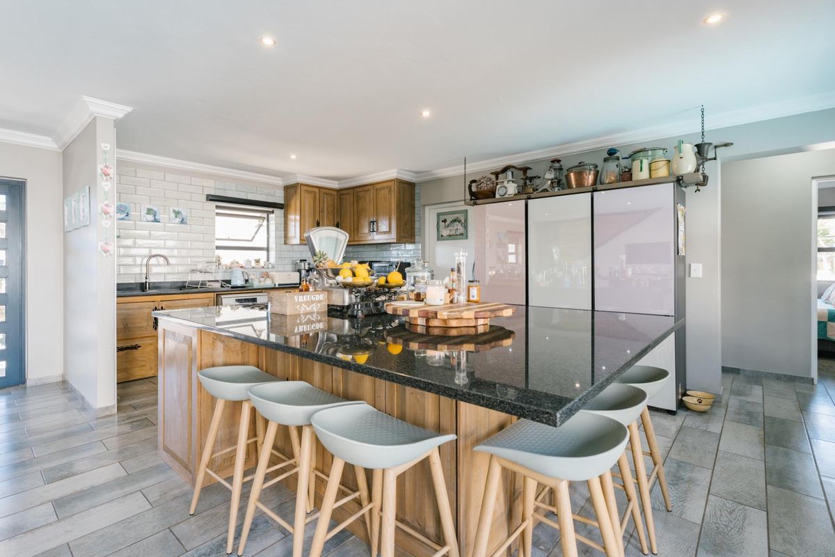 Spacious kitchen featuring a large central island with granite countertops, wooden cabinetry, subway tile backsplash, and modern recessed lighting.