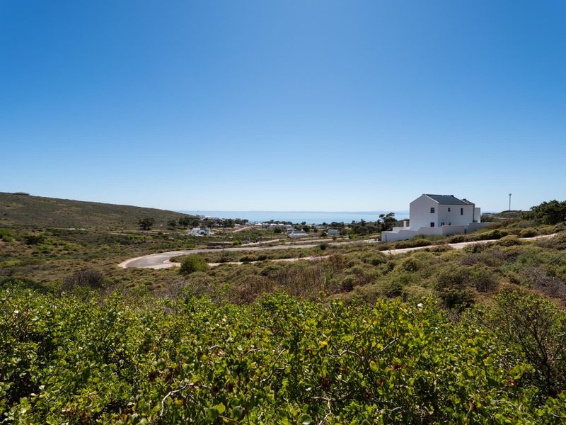 A scenic elevated view of the surrounding coastal landscape, featuring natural vegetation, a paved road, and distant ocean views.