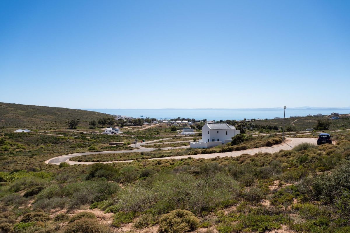 A scenic elevated view of the surrounding coastal landscape, featuring natural vegetation, paved access roads, and distant ocean vistas.