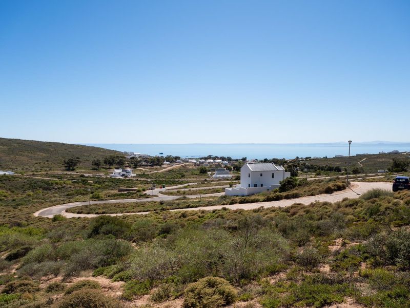 A scenic elevated view of the surrounding coastal landscape, featuring natural vegetation, paved access roads, and distant ocean vistas.