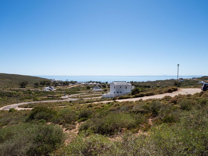 A scenic elevated view of the surrounding residential landscape, coastal terrain, and distant ocean horizon from the vacant land plot.