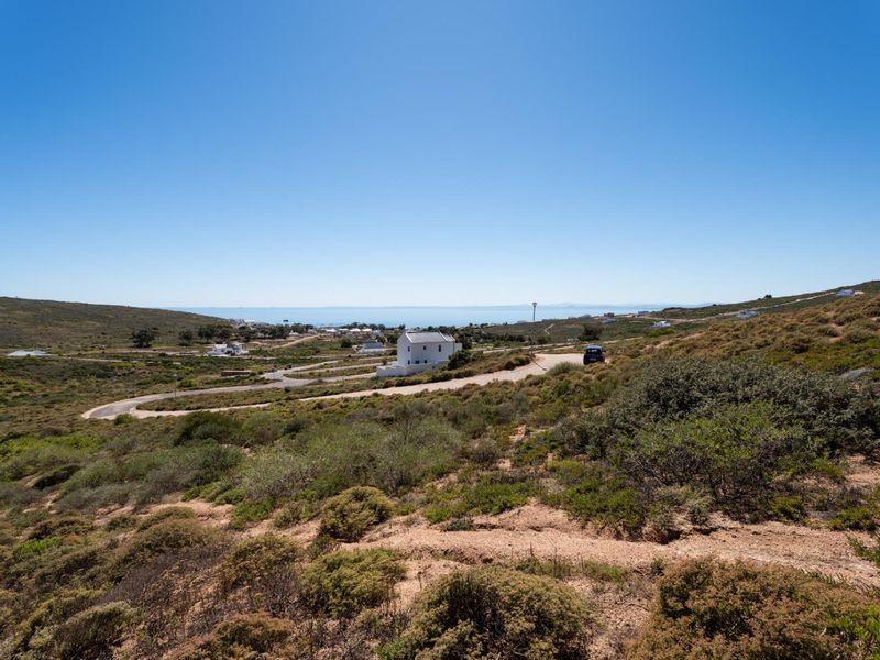 A wide-angle view of the surrounding coastal landscape and natural terrain, showcasing the open space and distant sea horizon.