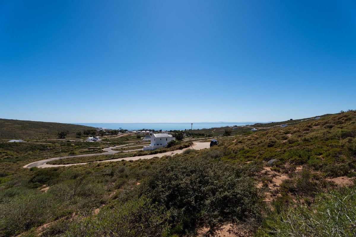 A wide-angle view of the coastal landscape and surrounding residential area, showcasing the natural terrain and access roads leading to the property.