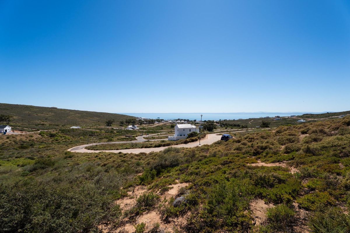 A scenic elevated view of the surrounding coastal landscape, featuring natural vegetation and a paved access road leading through the residential area.