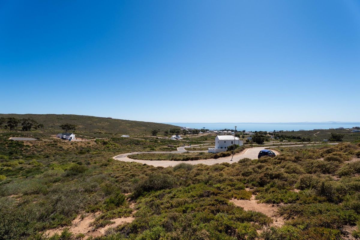 A scenic elevated view of the coastal residential estate, showcasing the natural landscape, winding access roads, and distant ocean horizon.