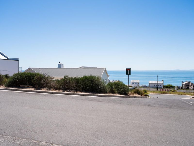A street-level view of the residential area, showcasing the paved road, surrounding landscape, and distant ocean views.