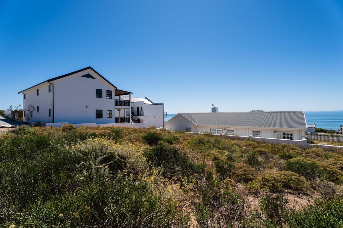 A view of the rear of the property showing surrounding residential buildings and coastal landscape with ocean views in the distance.