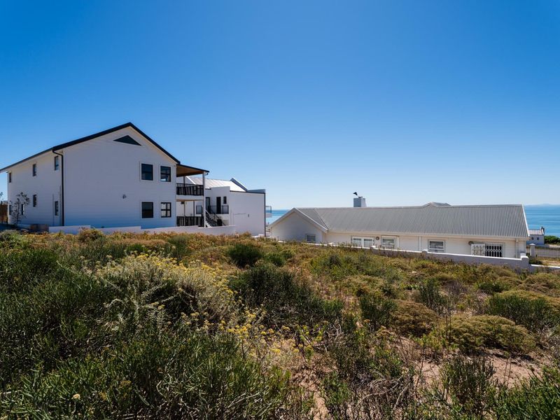 A view of the rear of the property showing surrounding residential buildings and coastal landscape with ocean views in the distance.