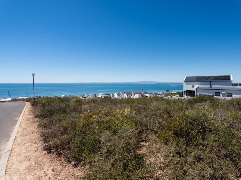 A scenic view of the ocean and coastal landscape from the vacant residential land, featuring paved street access.