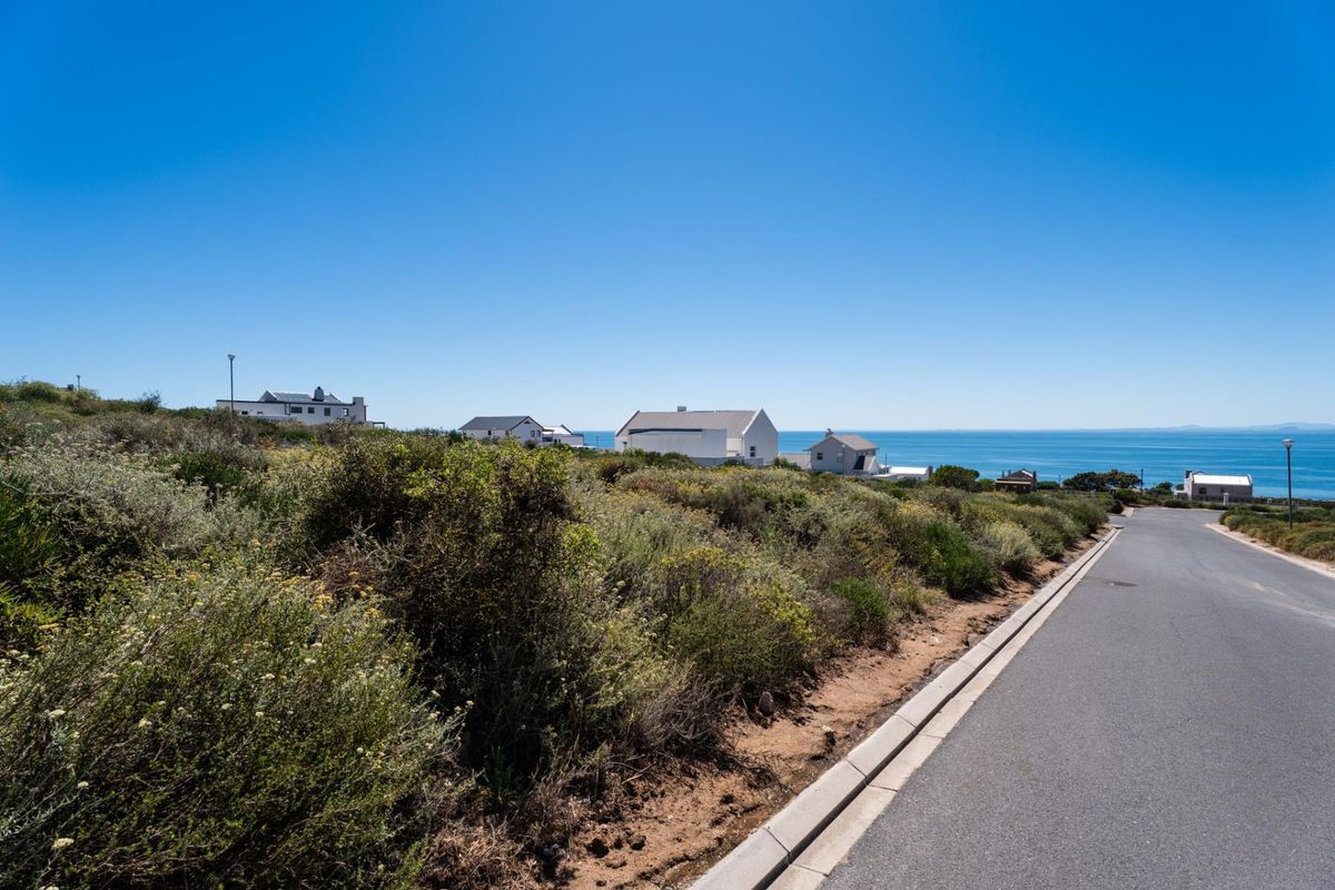 A view of the street frontage and surrounding coastal landscape, showcasing the vacant residential land and nearby established properties.