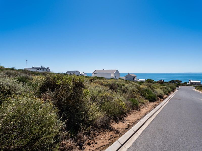 A view of the street frontage and surrounding coastal landscape, showcasing the vacant residential land and nearby established properties.
