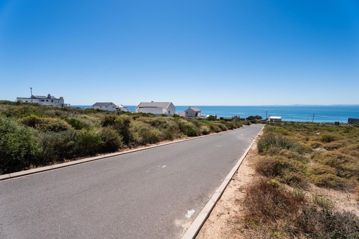 A view of the paved street leading through the residential area, featuring coastal landscape and ocean views in the background.
