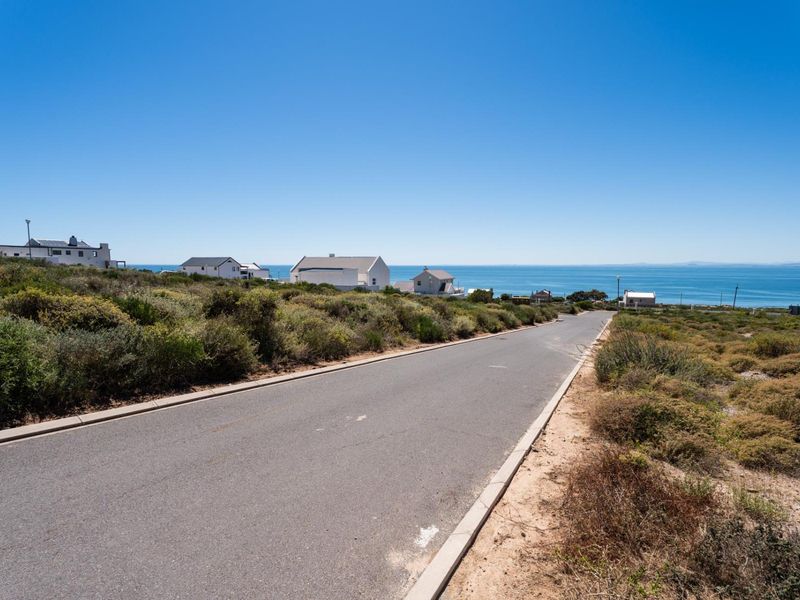 A view of the paved street leading through the residential area, featuring coastal landscape and ocean views in the background.
