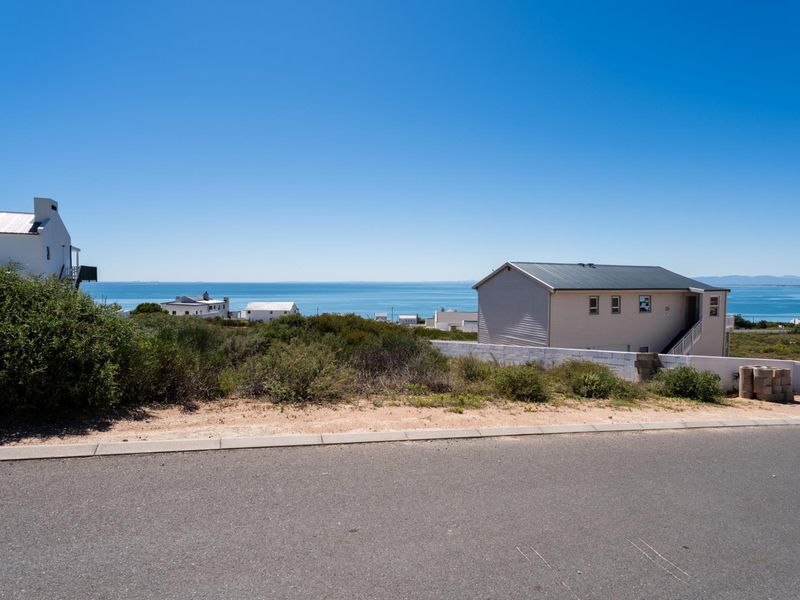 A clear view of the ocean and surrounding coastal landscape from the street level of this vacant residential property.