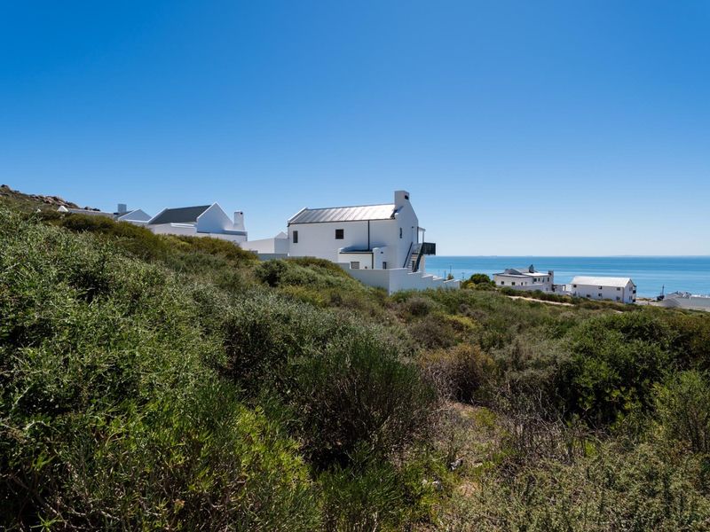 A scenic view of coastal residential properties nestled within natural vegetation overlooking the ocean.