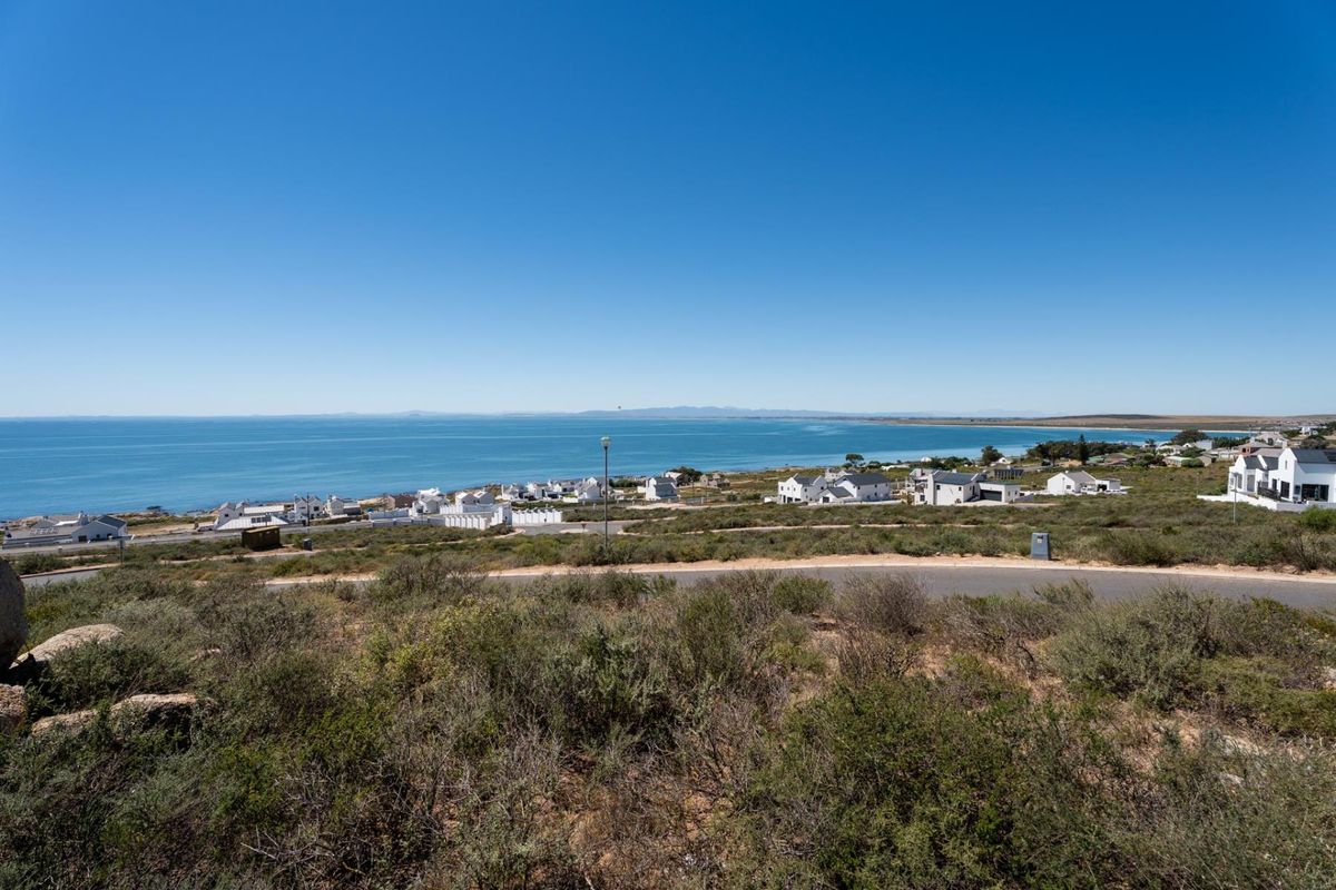 A scenic elevated view of the coastline, surrounding residential neighborhood, and paved road infrastructure.