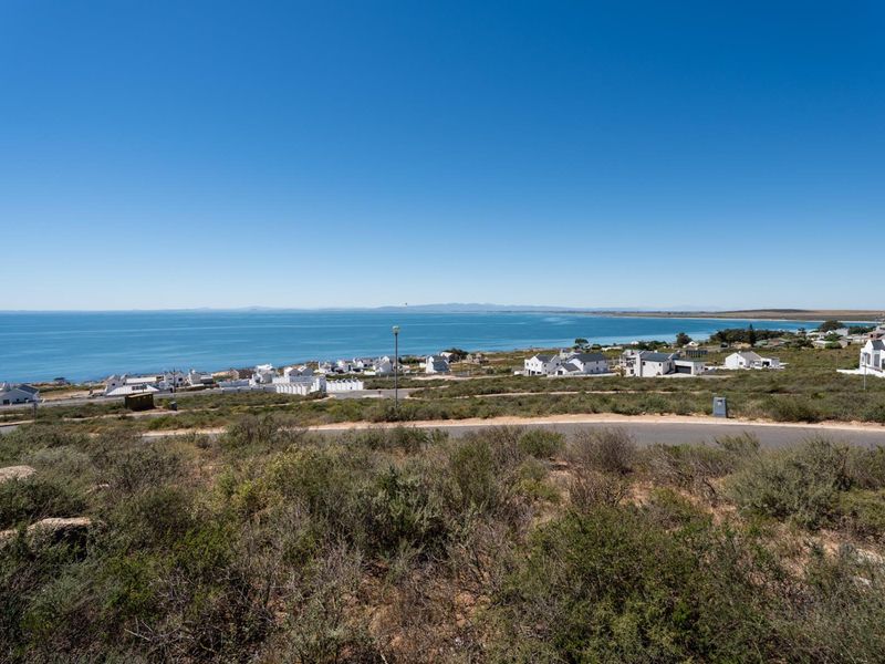 A scenic elevated view of the coastline, surrounding residential neighborhood, and paved road infrastructure.