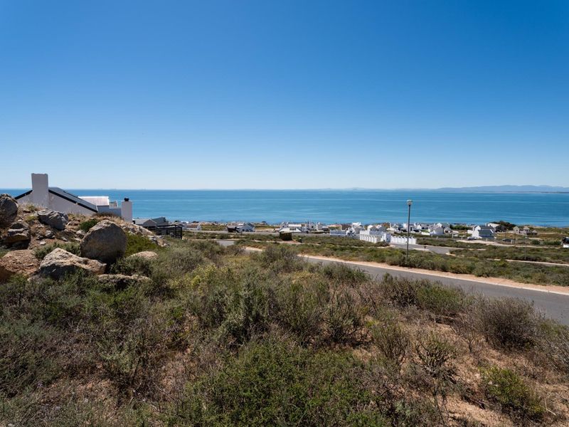 A scenic elevated view overlooking the coastal landscape, nearby residential properties, and the ocean horizon.