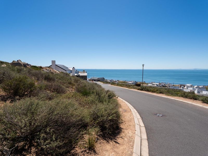 A view of the paved residential street leading towards the coastline, showcasing the surrounding landscape and coastal proximity.