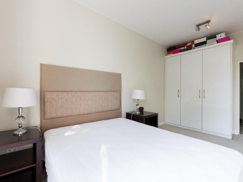A well-maintained bedroom featuring neutral walls, carpeted flooring, and a functional built-in wardrobe with ample storage space.