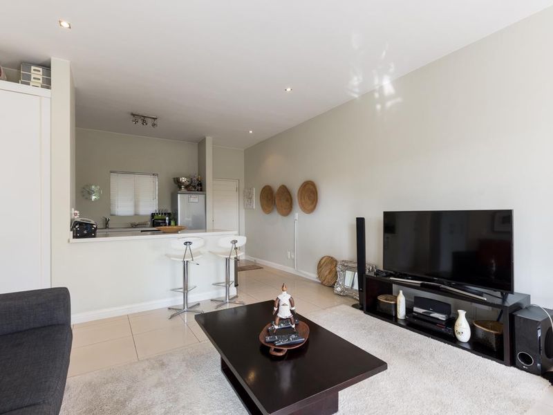 Open-plan living area featuring tiled flooring, recessed lighting, and a functional kitchen with a breakfast bar counter.