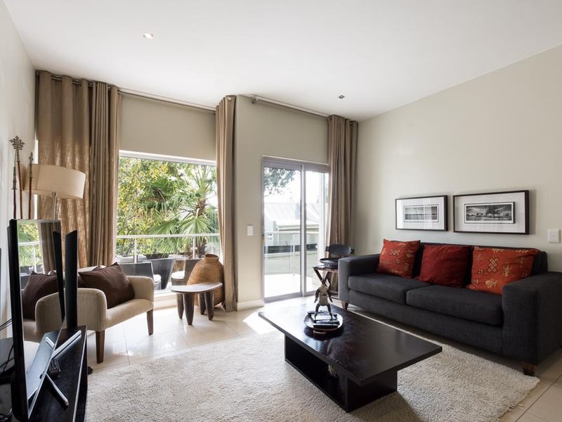 A bright and well-maintained living room featuring tiled floors, recessed lighting, and large sliding glass doors that provide access to an outdoor balcony.