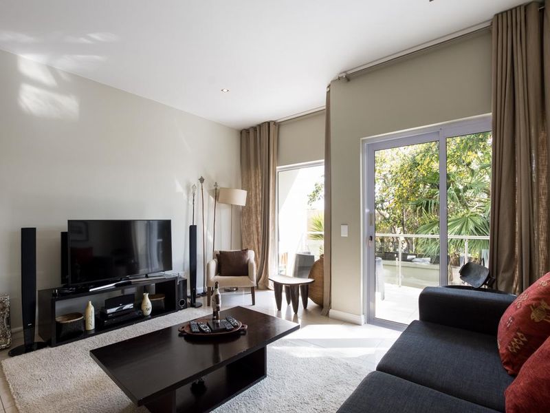 A bright living room featuring tiled floors, recessed lighting, and a large sliding glass door providing access to an outdoor balcony area.