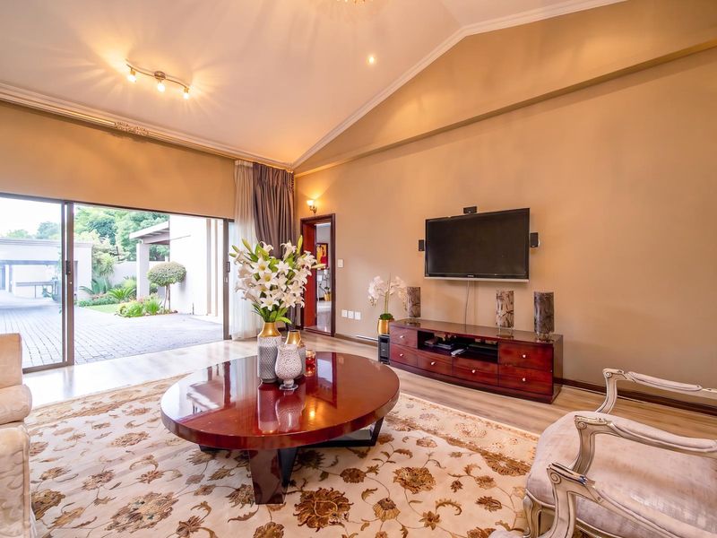 Spacious living room featuring a high vaulted ceiling, recessed lighting, and large sliding glass doors providing seamless access to the outdoor patio area.