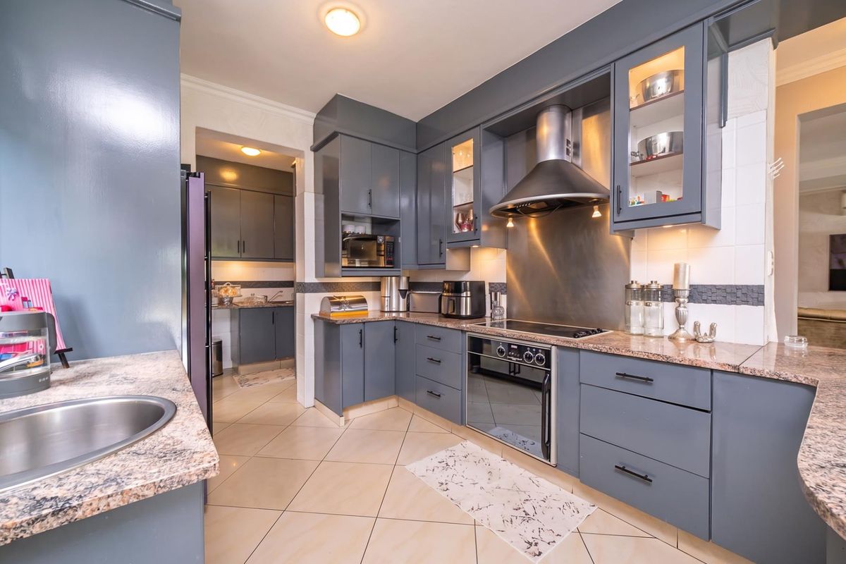 Modern kitchen featuring dark grey cabinetry, granite countertops, stainless steel appliances, and a functional scullery area with additional storage and workspace.
