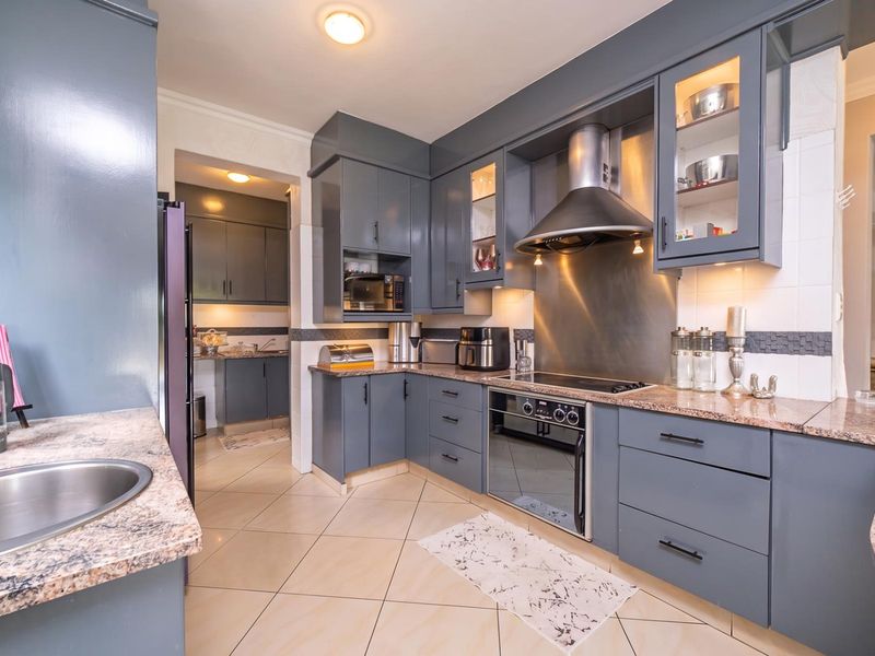 Modern kitchen featuring dark grey cabinetry, granite countertops, stainless steel appliances, and a functional scullery area with additional storage and workspace.