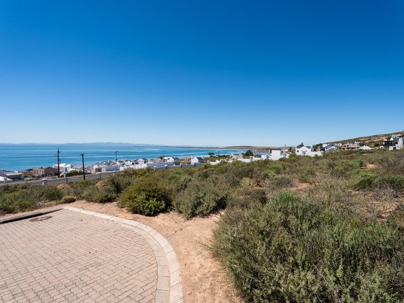 A scenic view overlooking the coastal landscape and residential area from a paved driveway on a vacant residential plot.