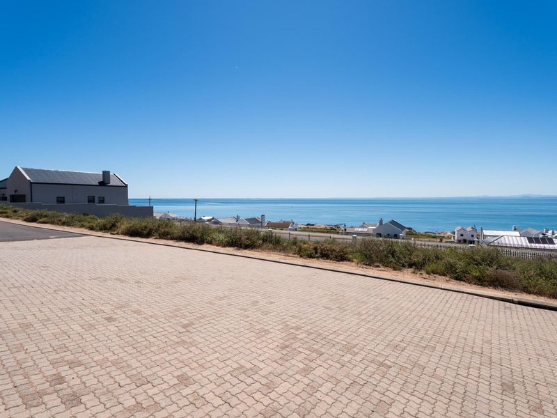 A clear, elevated view of the coastline and ocean from a paved residential street, showcasing the property's scenic location.