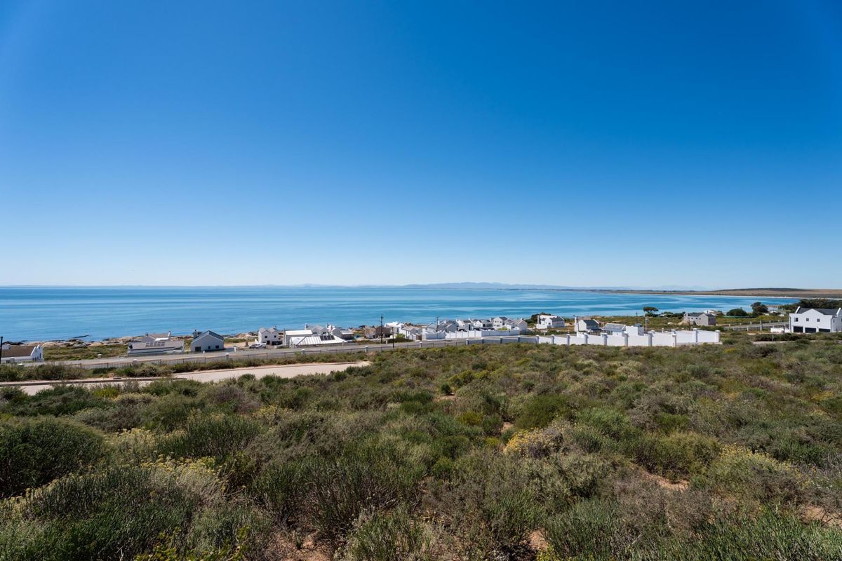 A scenic elevated view overlooking the coastline, ocean, and surrounding residential development from the vacant land plot.