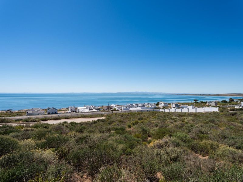 A scenic elevated view overlooking the coastline, ocean, and surrounding residential development from the vacant land plot.