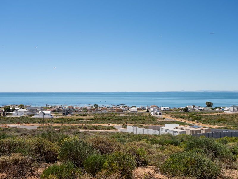 A scenic elevated view overlooking the coastal landscape, residential area, and the ocean horizon.