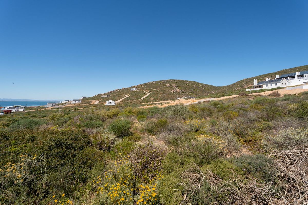 A wide-angle view of the vacant residential land, showcasing the natural coastal landscape and surrounding hillside terrain.