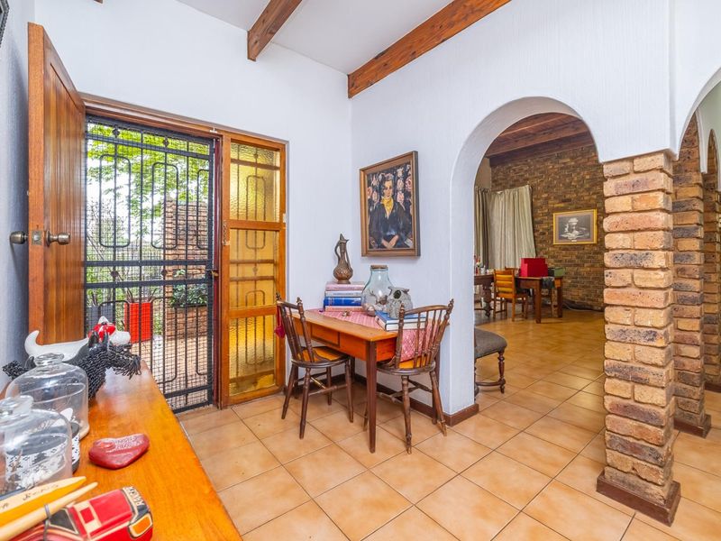 Entrance area featuring exposed timber ceiling beams, ceramic floor tiling, and a distinctive arched brick doorway leading into the living space.