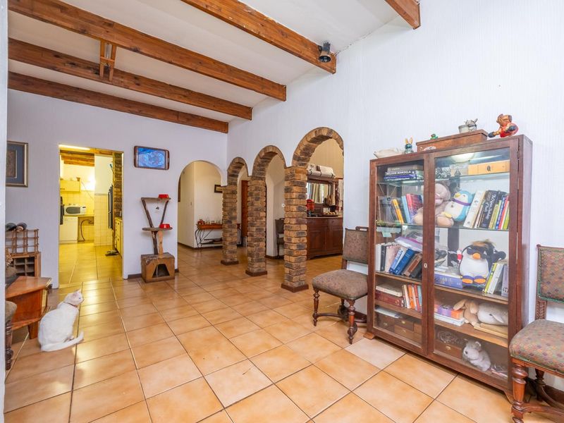 Spacious living area featuring distinctive brick archways and exposed timber ceiling beams, finished with durable ceramic floor tiles.