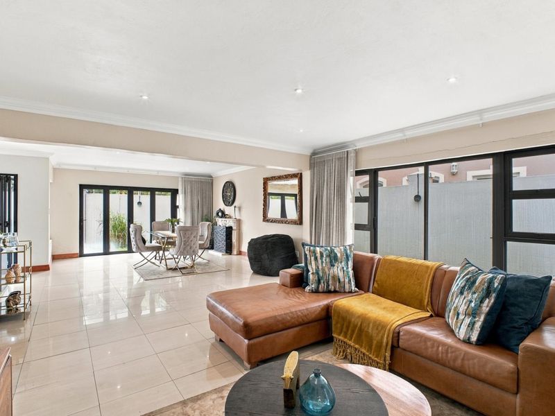 Spacious open-plan living and dining area featuring large format floor tiles, recessed lighting, and expansive aluminium sliding doors leading to the exterior.