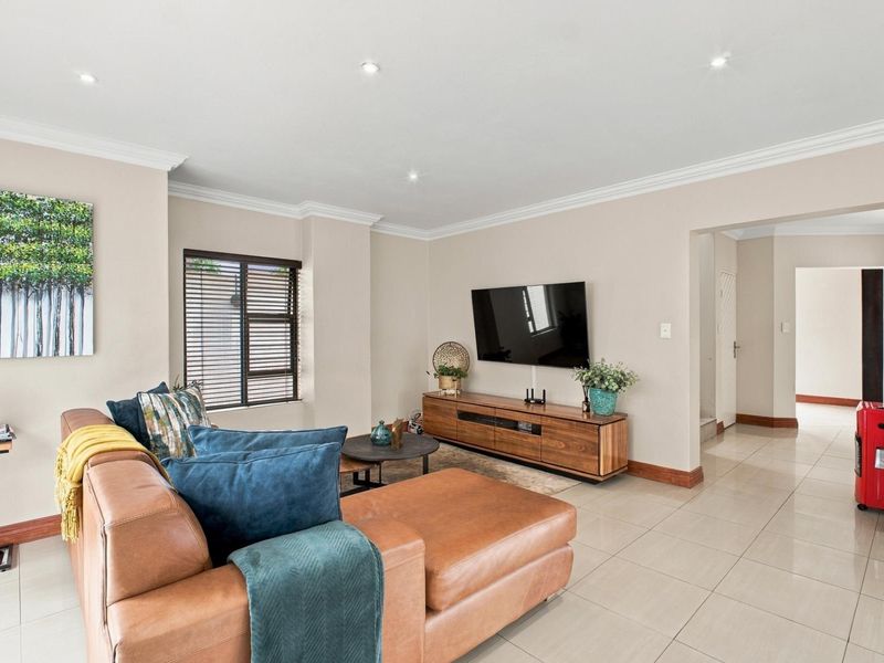 A well-maintained living room featuring neutral walls, tiled flooring, recessed downlighting, and crown molding, creating a bright and inviting space.