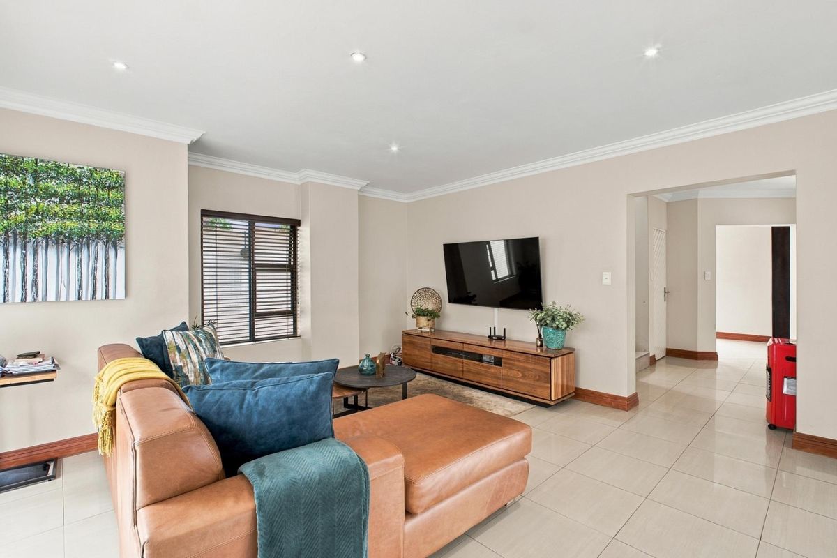 A well-maintained living room featuring neutral walls, tiled flooring, recessed downlighting, and crown molding, creating a bright and inviting space.