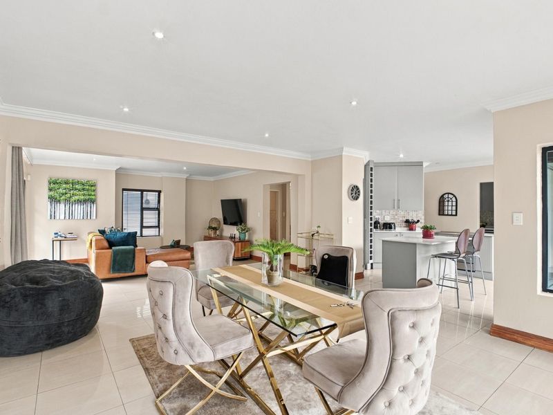 Spacious open-plan living and dining area featuring modern tiled floors, recessed lighting, and a contemporary kitchen with a central island.