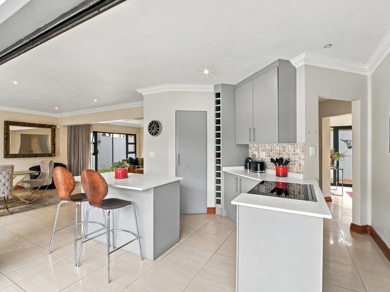 Modern open-plan kitchen featuring sleek grey cabinetry, stone countertops, and an integrated electric hob, seamlessly flowing into the adjacent living area.