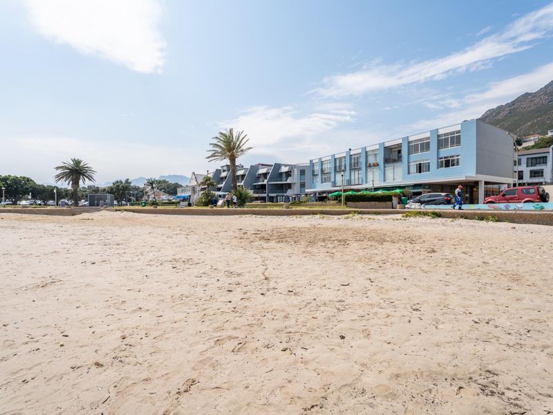 A view of the apartment building facade from the adjacent sandy beach, showcasing its prime coastal location and proximity to the promenade.