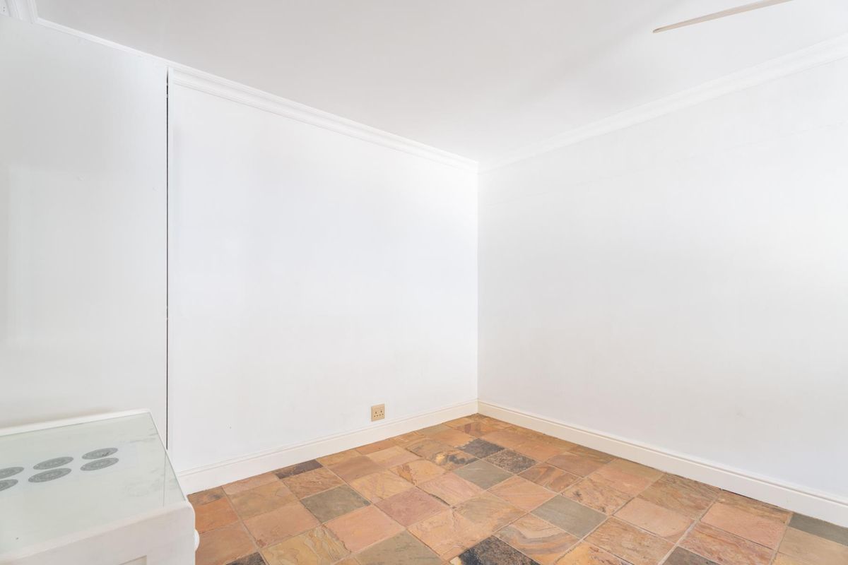 An empty bedroom featuring stone tile flooring, white walls, and a built-in cupboard, providing a blank canvas for personalization.