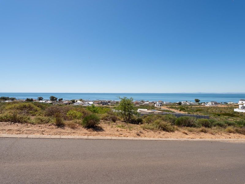 A scenic view of the coastline and ocean from the elevated vantage point of the residential vacant land.