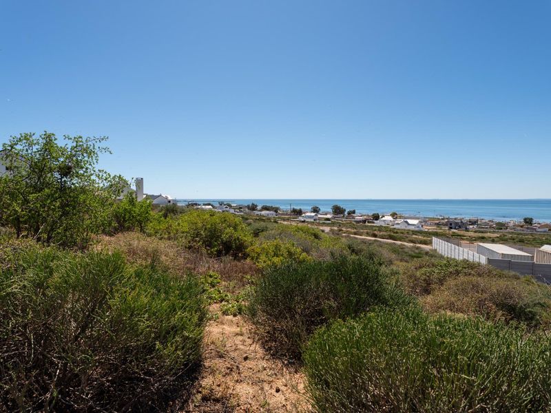 A scenic view overlooking the coastal landscape and nearby residential area from the vacant land plot.